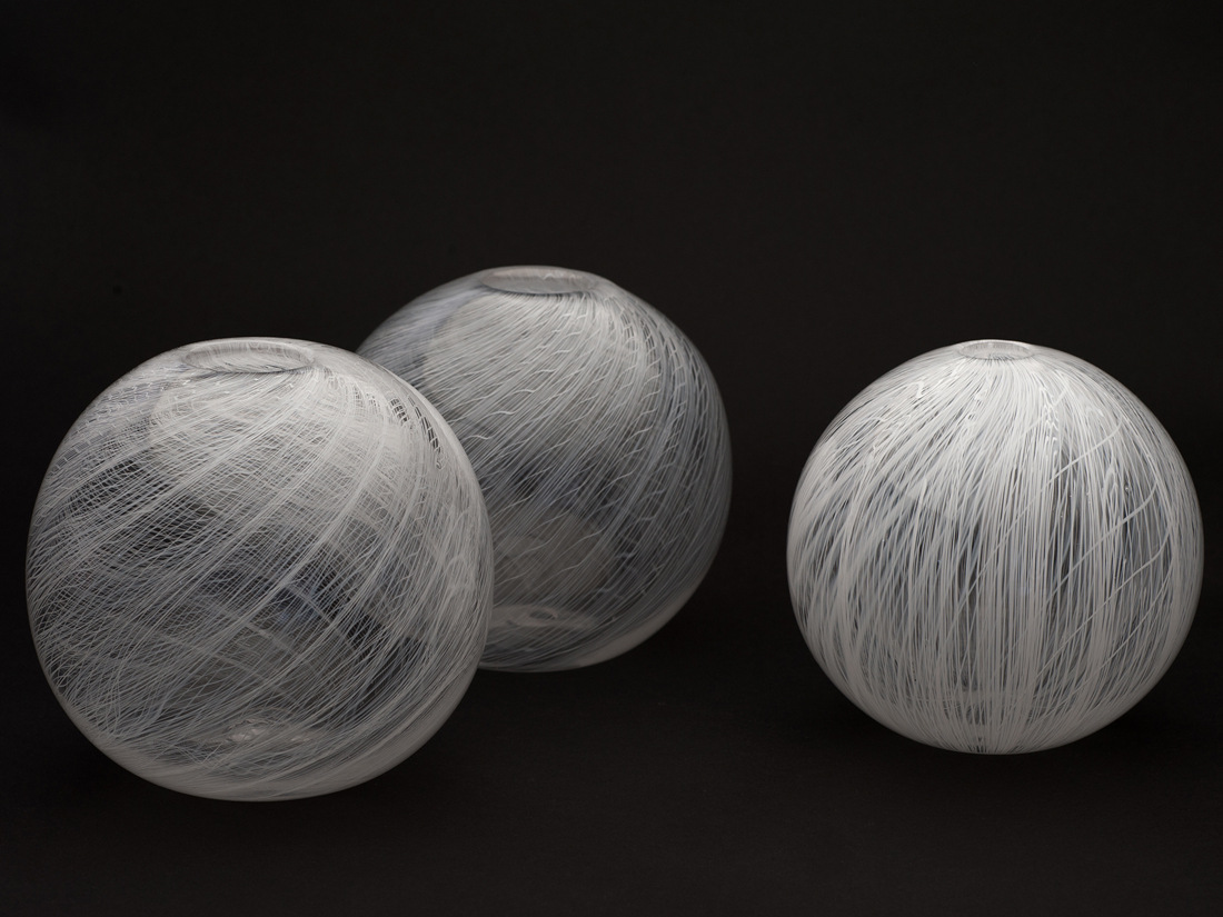 Glass sphere shapes with delicate fine flowing whilte lined patttern.